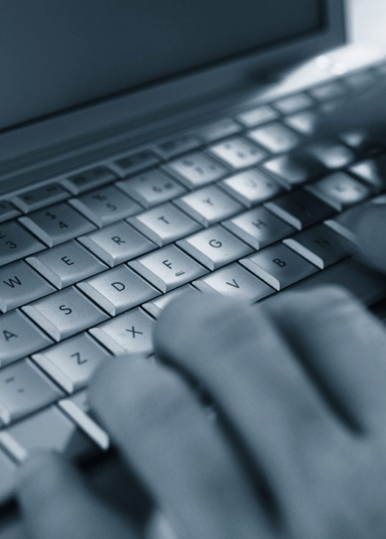 Nahaufnahme einer Hand, die über eine Laptop-Tastatur tippt.
